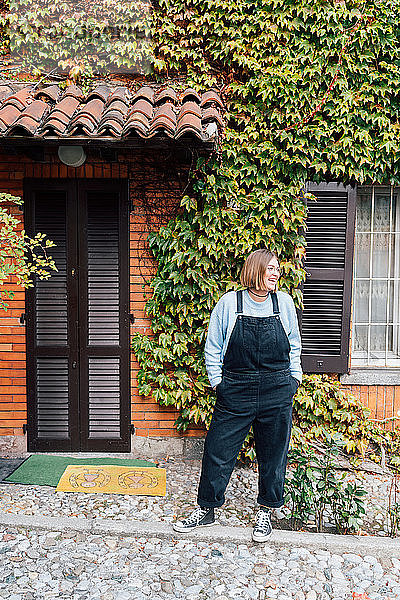 Frau vor Haus mit efeubewachsener Fassade  Rezzago  Lombardei  Italien