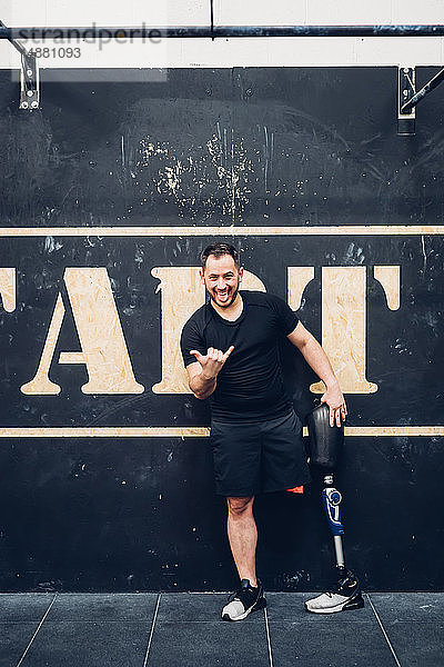 Mann mit Beinprothese lehnt in Turnhalle an Wand