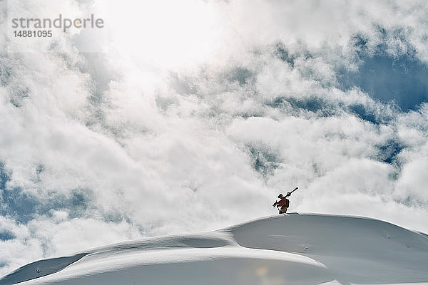 Männlicher Skifahrer auf dem Gipfel eines schneebedeckten Berges  Alpe-d'Huez  Rhône-Alpes  Frankreich