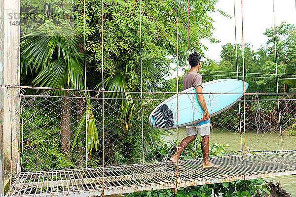 Mann mit Surfbrett auf Seilbrücke  Pagudpud  Ilocos Norte  Philippinen