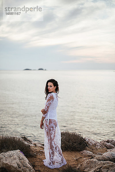 Glamouröse Frau in langem weißen Spitzenkleid an der Küste  Porträt  Santa Teresa Gallura  Sardinien  Italien