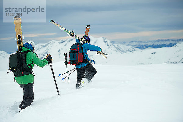 Landschaft mit zwei männlichen Skifahrern  die sich auf den Berg zubewegen  Rückansicht  Alpe-d'Huez  Rhône-Alpes  Frankreich