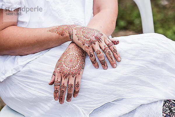 Frau in weißem Kleid mit Henna-Tattoo auf den Händen