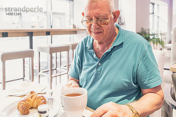 Älterer Mann beim Frühstück im modernen Café