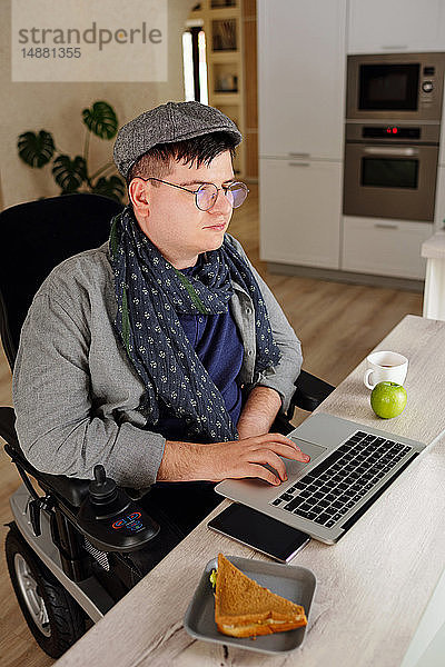Körperlich behinderter Mann arbeitet zu Hause am Laptop