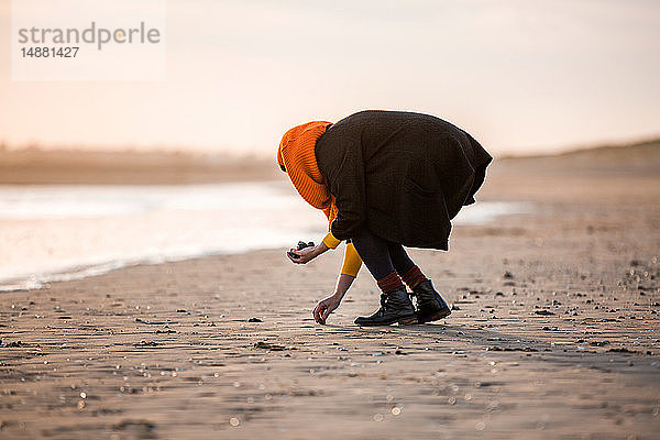 Frau sammelt Kieselsteine am Strand