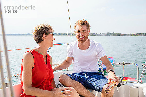 Junger Mann und reife Frau lachend auf einem Segelboot auf dem Chiemsee  Bayern  Deutschland