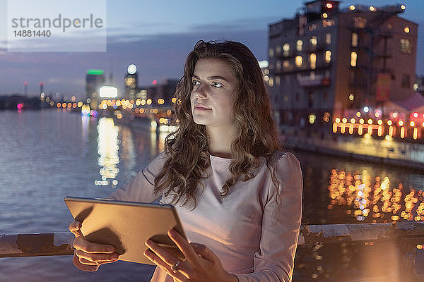 Junge Frau mit digitalem Tablett auf Brücke  Fluss und Stadt im Hintergrund  Berlin  Deutschland