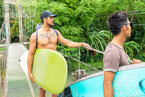 Männer mit Surfbrettern auf Seilbrücke  Pagudpud  Ilocos Norte  Philippinen