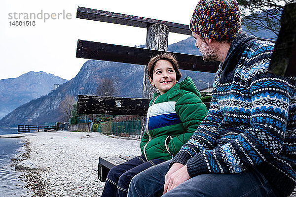 Junge und Vater sitzen plaudernd am Pier des Comer Sees  Comer See  Onno  Lombardei  Italien