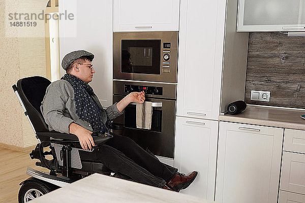 Körperbehinderter Mann schaltet Ofen in Küche ein