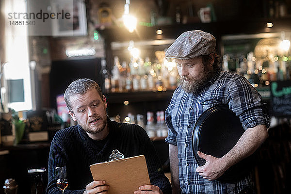 Barkeeper serviert Kunden  die sich die Speisekarte in einem traditionellen irischen Wirtshaus ansehen