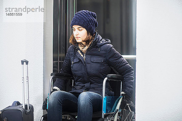 Frau im Rollstuhl mit Gepäck