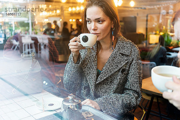 Junge Frau trinkt Kaffee mit einem Freund in einem Café  London  Großbritannien