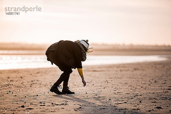 Frau sammelt Kieselsteine am Strand