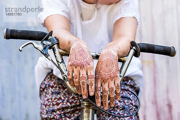 Frau mit Henna-Tattoo an den Händen auf dem Fahrrad sitzend