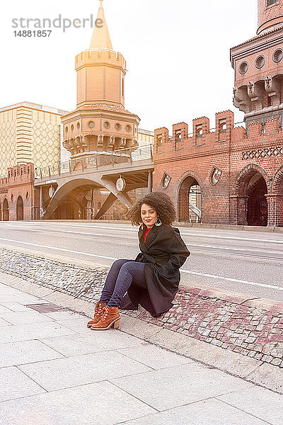 Mittlere erwachsene Frau in stilvollem Mantel auf der Oberbaumbrücke sitzend  Porträt  Berlin  Deutschland