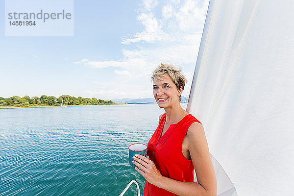 Reife Frau trinkt Kaffee beim Segeln auf dem Chiemsee  Bayern  Deutschland