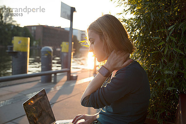 Junge Frau mit Laptop vor einem Café  Berlin  Deutschland