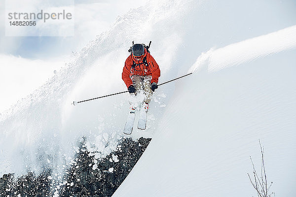 Männlicher Skifahrer fährt in der Luft einen schneebedeckten Berg hinunter  Alpe-d'Huez  Rhône-Alpes  Frankreich