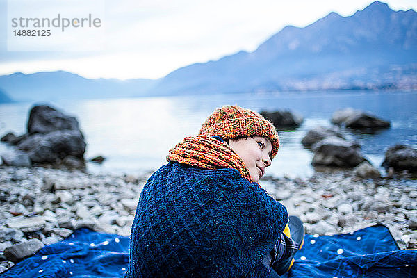 Junge sitzt auf einer Decke am Seeufer  Comer See  Onno  Lombardei  Italien