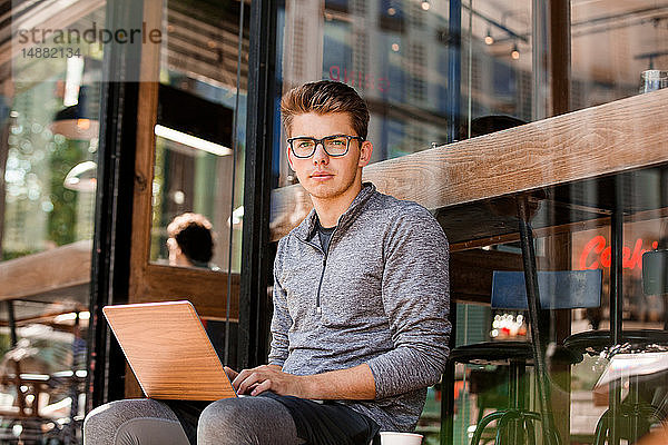 Junger Mann mit Laptop im Café  London  Großbritannien