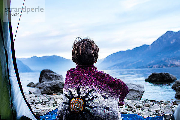Junge blickt vom Zelt aus auf den See  Rückansicht  Comer See  Onno  Lombardei  Italien