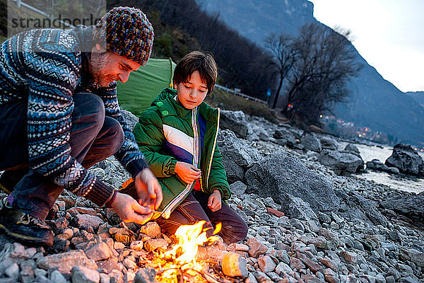 Vater und Sohn toasten Marshmallows über dem Lagerfeuer  Onno  Lombardei  Italien