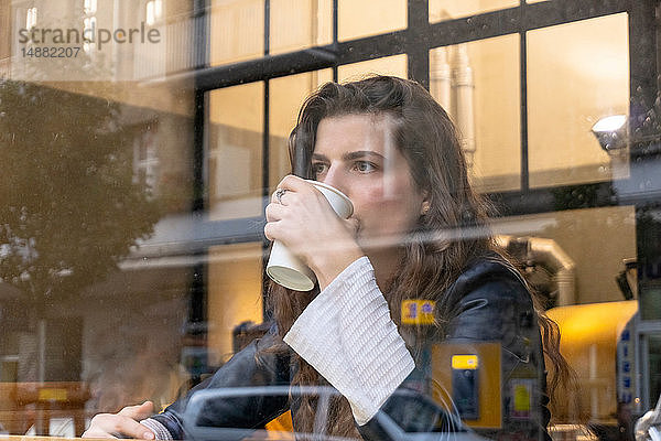 Junge Frau genießt heißes Getränk im Café