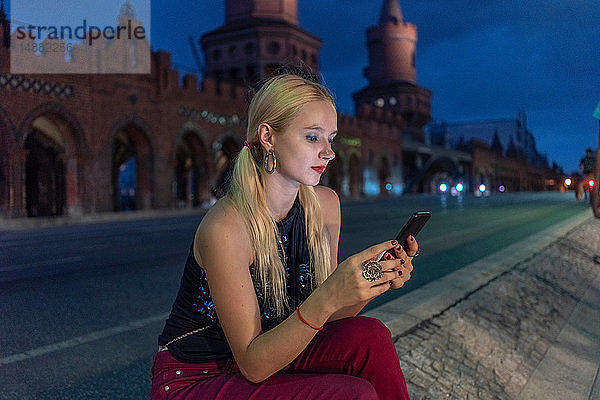 Hipster-Frau schreibt am Straßenrand  Berlin  Deutschland