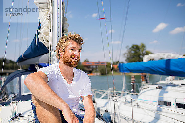 Junger Mann sitzt auf einem Segelboot auf dem Chiemsee  Bayern  Deutschland