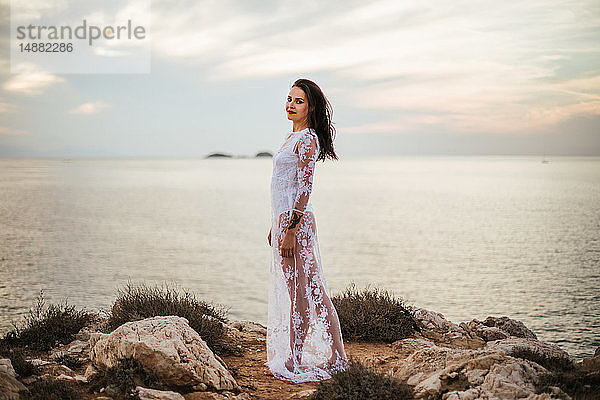 Glamouröse Frau in langem weißen Spitzenkleid an der Küste  Porträt  Santa Teresa Gallura  Sardinien  Italien