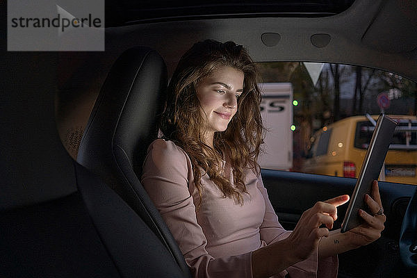 Junge Frau benutzt digitales Tablett im Auto
