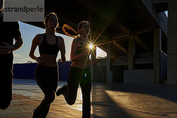 Freunde joggen bei Sonnenuntergang im Sportstadion