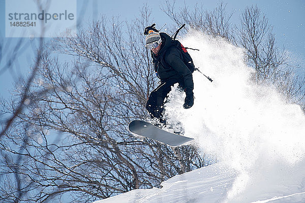 Männlicher Snowboarder beim Snowboarden in der Luft am Berghang  Alpe-d'Huez  Rhône-Alpes  Frankreich