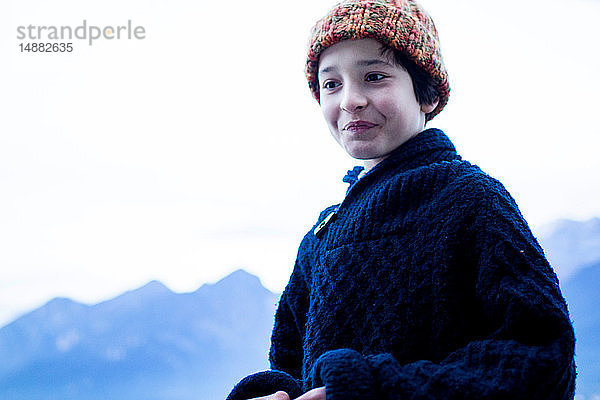 Porträt eines Jungen in Winterwollen  im Hintergrund Gebirge