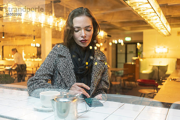 Junge Frau benutzt ein Smartphone in einem Café  London  UK