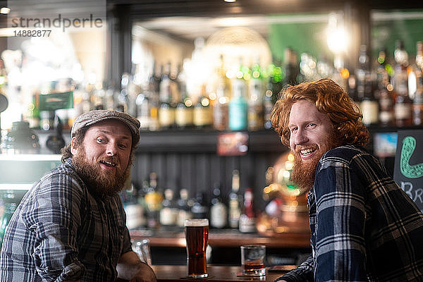 Zwei männliche Gäste  die von einer Bar in einer traditionellen irischen Kneipe über die Schulter schauen