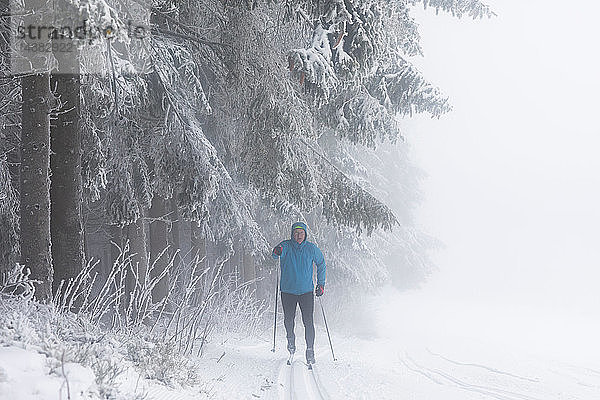 Skilanglauf eines erwachsenen Mannes durch Nebelwald  in voller Länge