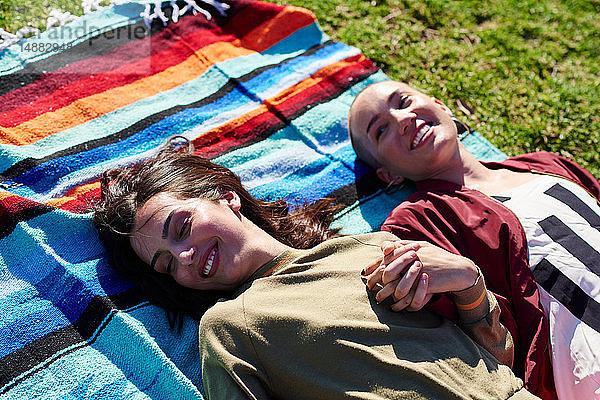 Zwei junge Freundinnen liegen auf einer Picknickdecke im Park  Los Angeles  Kalifornien  USA