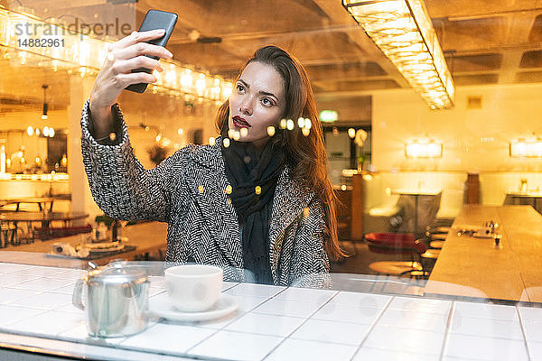 Junge Frau  die sich im Café mit einem Smartphone selbstständig macht  London  UK