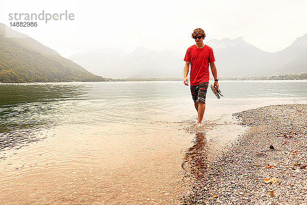 Junger Mann paddelt knöcheltief im See von Annecy  Annecy  Rhône-Alpes  Frankreich