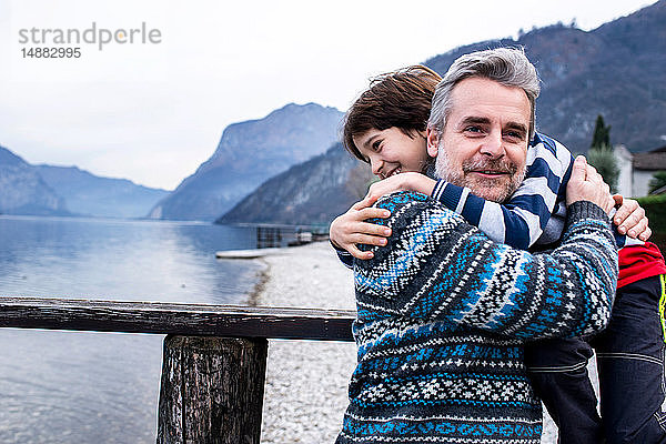 Junge und Vater umarmen sich am Pier des Comer Sees  Comer See  Onno  Lombardei  Italien