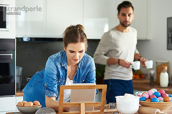 Ein Paar trinkt Kaffee und benutzt ein digitales Tablett in der Küche