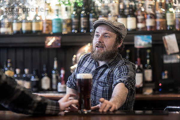 Barmann serviert Bier an einer Bar in einem traditionellen irischen Lokal