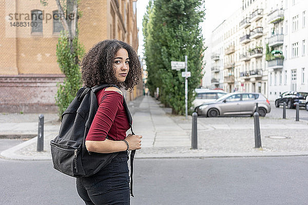 Junge Frau mit Rucksack auf der Straße  Berlin  Deutschland