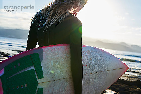 Surfer mit Surfbrett am Strand