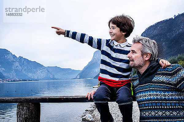 Junge und Vater zeigen vom Pier am Seeufer  Comer See  Onno  Lombardei  Italien