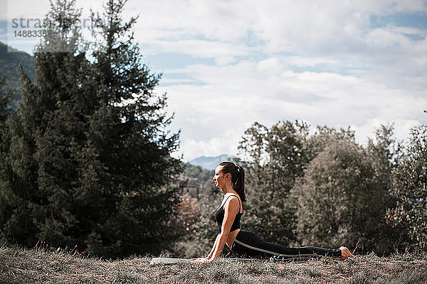 Yoga praktizierende Frau  auf Yogamatte in ländlicher Landschaft