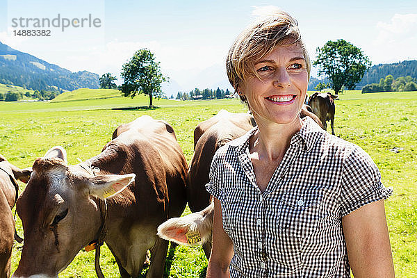 Frau verbindet sich mit Kuhherde auf dem Feld  Sonthofen  Bayern  Deutschland